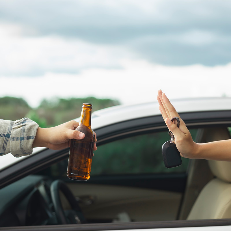 Abbildung zeigt, dass Alkohol am Steuer verboten ist.